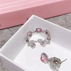 Detail of pink heart-shaped zircon ring and earring set in a white jewelry box