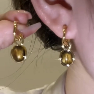Detailed close-up of oval tiger eye stud earrings with gold plating and minimalist design
