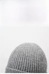 Close-up of grey ribbed knit beanie showing thick vertical texture and folded cuff detail