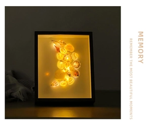 Close-up of DIY shell decorative shadow box with warm LED lighting and black frame