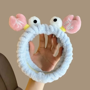 Detail of soft plush light blue crab headband with pink pincers and embroidered characters