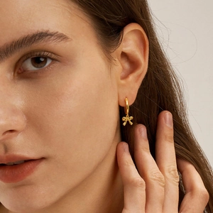 Elegant gold bow earrings for women featuring a minimalist ring and refined metal pendant