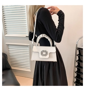 Detail showing the large crystal buckle on the white leather square crossbody bag