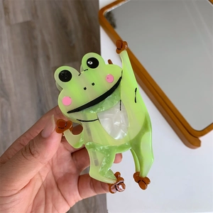 Detailaufnahme einer grünen Haarklammer aus Essigsäure in Form eines Frosches mit Perlmutt
