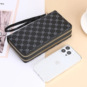 Detail view of black dual-zipper long wallet with geometric floral pattern and wrist strap