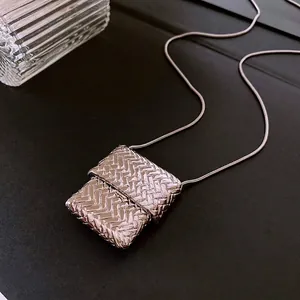 Silver square woven pendant necklace with sleek snake chain on a dark textured surface
