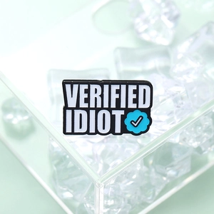 Badge en émail métallique Verified Idiot avec coche bleue sur fond vert pastel