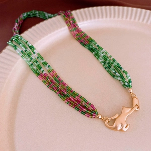 Detailed macro view of multi-layer beaded necklace with green beads and cat charm