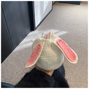 Close-up of handmade white crochet bucket bag with pink rabbit ears and drawstring