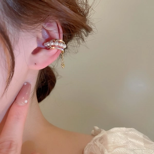 Detail of gold layered ear cuff with pearls, zircon, and dangling heart charm on model