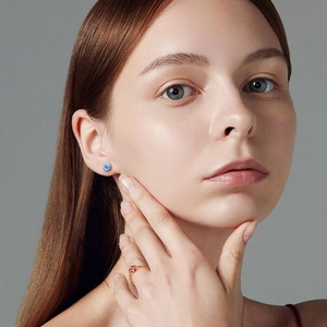 Elegant woman wearing silver zircon stud earrings, rose gold ruby ring and fine gold necklace