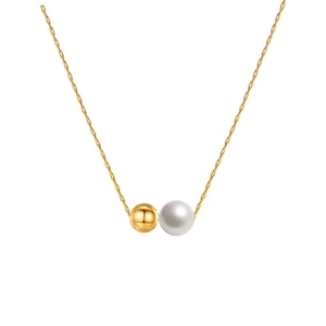 Detailed macro view of the minimalist gold metal bead and white pearl pendant on fine O-chain