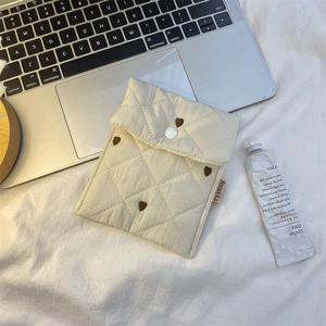 Close-up of quilted apricot toiletry bag featuring brown heart embroidery and snap closure