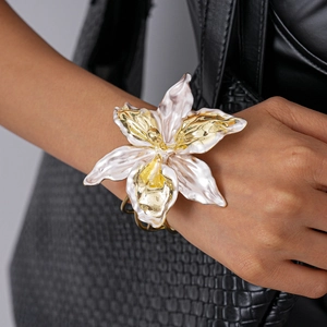 Detailed close-up of large orchid floral cuff bracelet with pearl enamel and gold finish