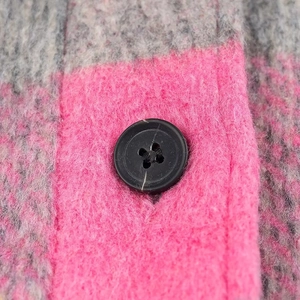 Detail of pink and grey plaid fabric texture with a black button on flannel jacket