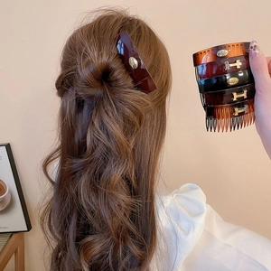Detail of vintage acrylic oval hair comb with gold H logo and tortoise shell pattern