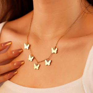 Detail of five gold butterfly charms hanging from a minimalist fashion choker necklace