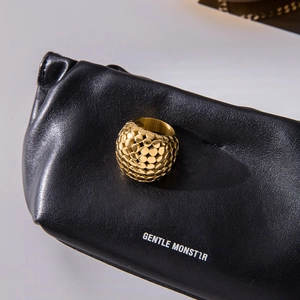 Bague sphérique dorée avec surface texturée sur fond de cuir noir élégant
