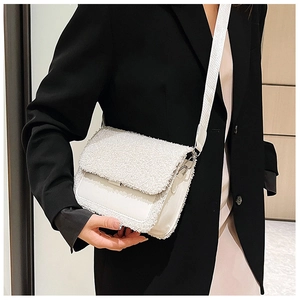 Detail of white faux shearling and leather patchwork handbag with wide strap worn by model