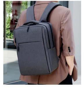 Man wearing waterproof dark grey business backpack with padded straps in urban setting
