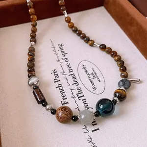 Close-up of tiger eye stones, wooden beads, and blue glass pendant on a beaded necklace