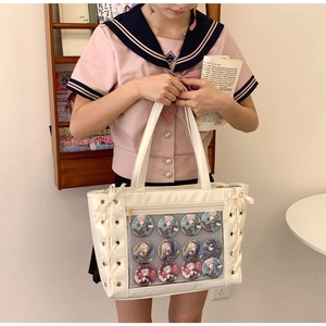 Detail of white ita bag showing a large transparent display window filled with 12 anime badges
