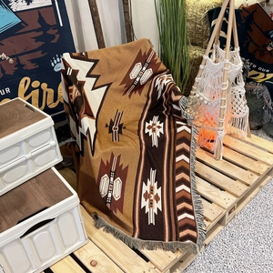 Bohemian geometric camping blanket with decorative fringe on a natural wooden tray