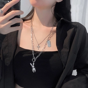 Detail of layered silver necklaces with cross pendant and HOPE tag on a model