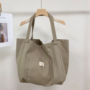 Detail of minimalist khaki canvas tote bag with contrast stripe and front pocket