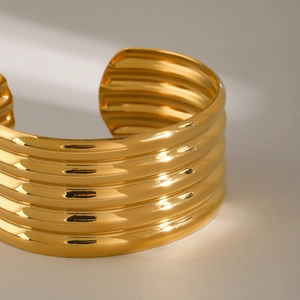 Macro detail of high-polish 18k gold stainless steel multi-layered textured open cuff