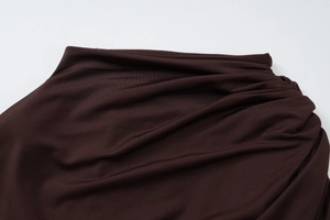 Gros plan sur les détails froncés et la texture jersey d'une robe moulante marron