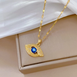 Luxurious gold evil eye pendant necklace with sparkling pavé crystals on silk background