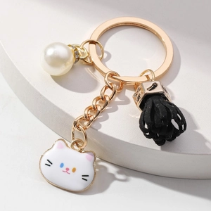 Golden keychain with cute white cat charm, pearl rhinestone, and black tassel pendant