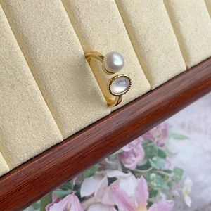 Detail of adjustable gold ring with freshwater pearl and shell inlay on velvet display