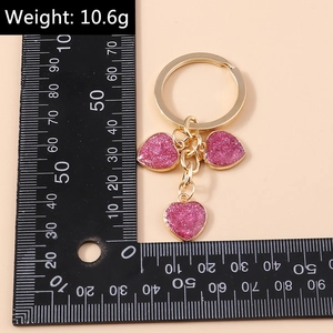 Detailed view of pink glitter heart keychain with gold plating and measurement scale