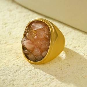 Vintage stainless steel gold ring with pink natural stone inlay on beige texture