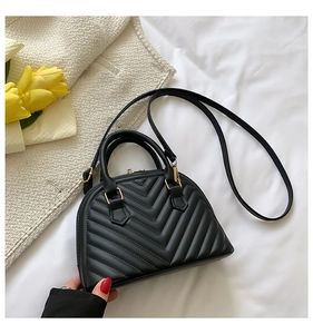 Detail of a black quilted shell handbag featuring matte PU leather and metal hardware