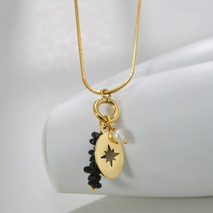 Detail of bohemian gold starburst pendant with black natural stones and white pearl