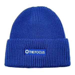 Detailed close-up of dark blue ribbed beanie with The Focus logo embroidery patch