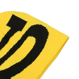 Makro-Detail einer hochwertigen gelben Strickmütze mit schwarzer Jacquard-Buchstabenwebung