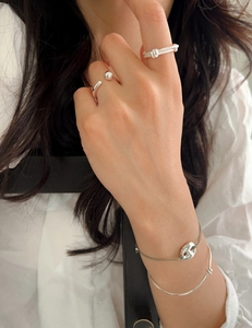 Close-up of elegant double-layered knotted silver rings and bracelets on model