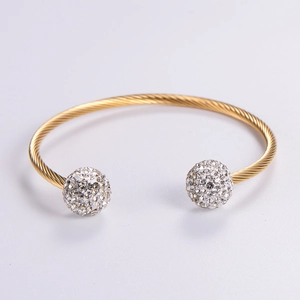 Minimalist twisted gold bangle featuring sparkling crystal-encrusted spheres on both ends