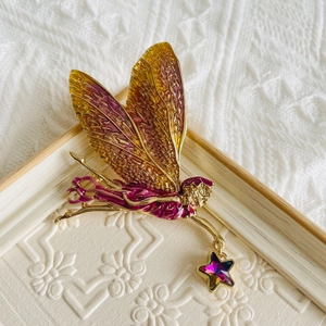 Close-up of golden fairy brooch with purple enamel wings and a crystal star charm
