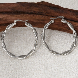 Detailed view of 304 stainless steel silver twisted hoop earrings on wooden decor