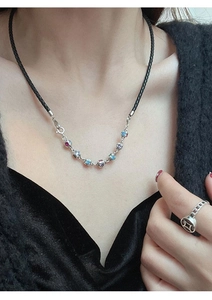 Close-up of a black cord necklace with silver dice pendants and colorful gemstones