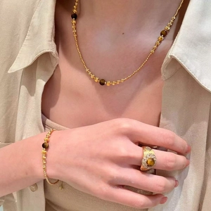 Detail of 18k gold plated necklace and tiger eye bead jewelry set on a female model
