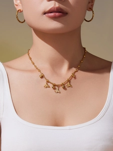 Detailopname van een gouden bijenketting met steentjes gedragen door een model als sieraad