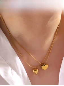 Close-up of a 18K gold-plated heart pendant necklace with double layered snake chain on neck