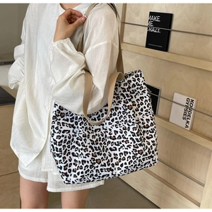 Gros plan d'un sac cabas en toile à imprimé léopard porté par un mannequin en chemise blanche