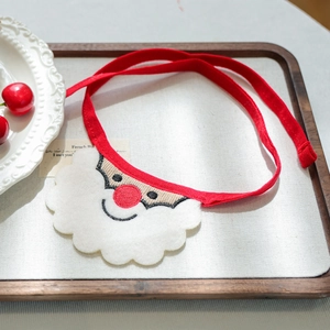 Detail of Christmas Santa beard pet bib with red nose and ties on a wooden tray